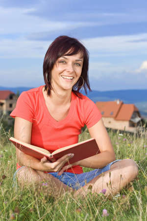 Young woman lying on the grass and reading book outdoor の写真素材