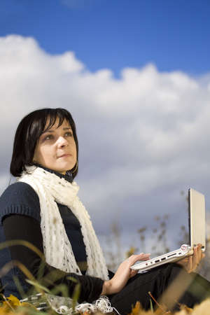 Close-up portrait of an beautiful autumn girl student working with laptopの写真素材
