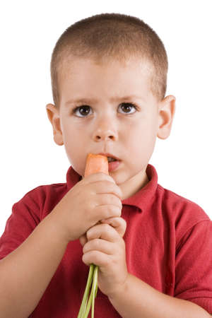three years old boy eating fresh carrot isolated on white の写真素材