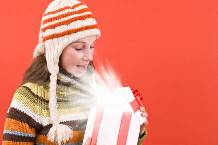 Surprised woman open a magic Christmas gift with lightsの写真素材