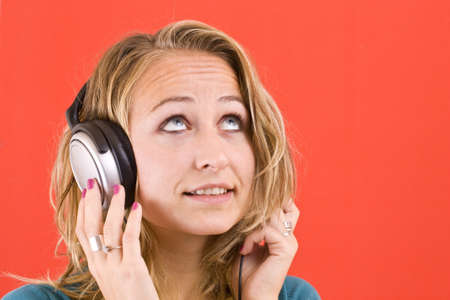 Happy woman with headphones lying down on sofa in lounge, listen to music の写真素材