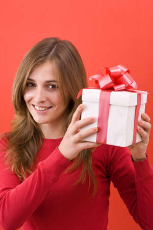 surprised Girl holding a gift , on red background. の写真素材