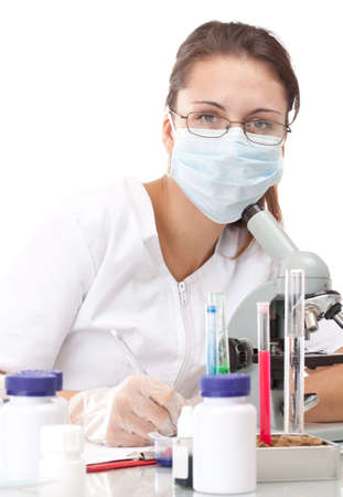 Woman working with a microscope and writing her experimentの写真素材