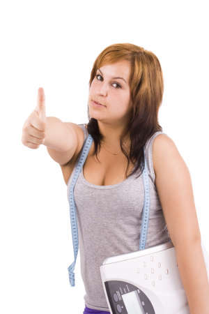Young healthy woman  carrying a weight scale over white background の写真素材