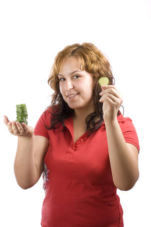 a young, beautiful, happy woman is holding some cucumber in front of her face の写真素材