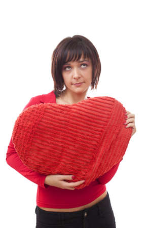 Beautiful young woman with red heart-shaped pillow over white の写真素材