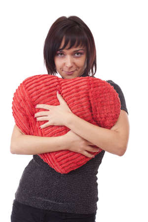 Beautiful young woman embrace a red heart-shape pillow の写真素材