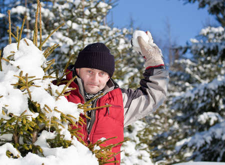 Young man outdoor in winter park enjoying playing with snowball