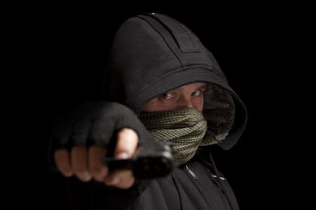Thief with gun aiming into a cameraの写真素材