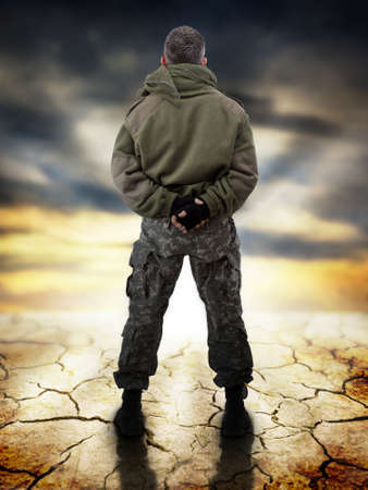Military standing - back view, looking for apocaliptic sunriseの写真素材