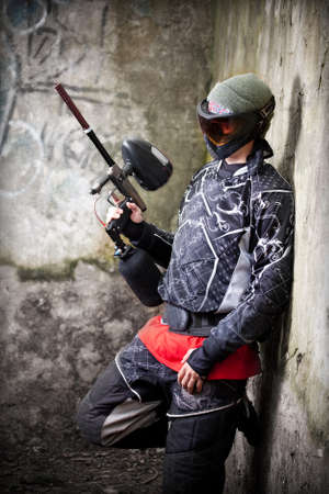 Paintball player relaxing with marker in grunge backgroundの写真素材