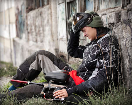 Paintball player relaxing with marker in grunge backgroundの写真素材