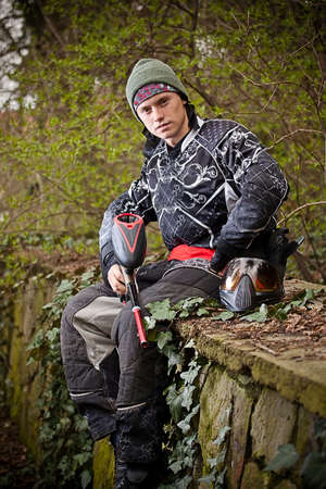 Paintball player relaxing with marker in grunge backgroundの写真素材