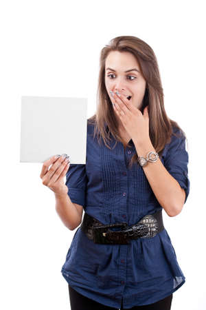 Portrait of a surprised young woman looking at a blank card isolated over white backgroundの写真素材