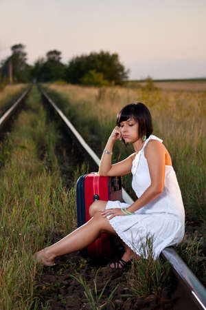 Attractive young woman with suitcase standing along the railの写真素材