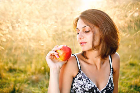 Beautiful young woman with apple at meadow の写真素材