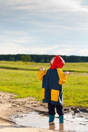 Boy in a muddy puddle waiting rain の写真素材