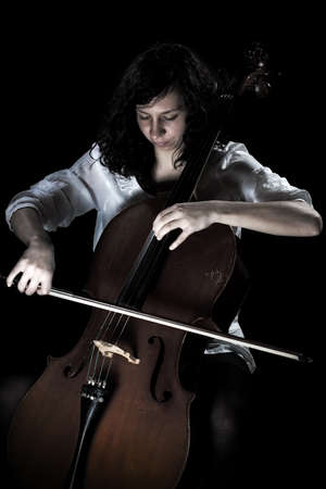 girl playing cello, in black backgroundの写真素材