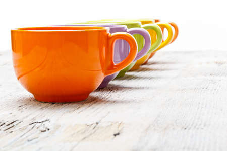 Row of color tea cups on old wood table