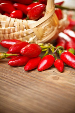 Basket of red hot chili peppers on the wooden background の写真素材