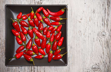 Chili Peppers on plate over wooden background の写真素材