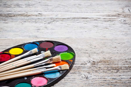 Brush and paints on old wood backgroundの写真素材