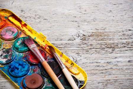Messy, used watercolor paint box and paint brush の写真素材
