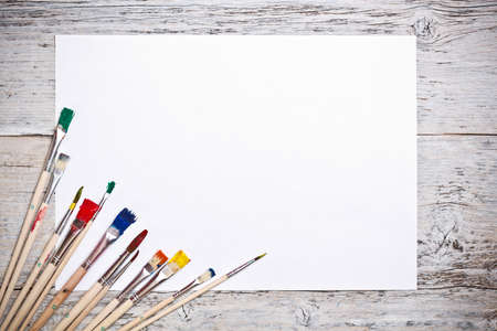 Set of used paint bruches with paper on wood backgroundの写真素材