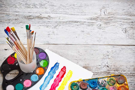 Box of watercolors and paintbrushes on wooden desk の写真素材