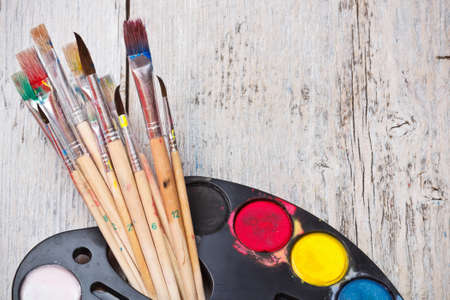 Watercolor paint with brush on wood background
