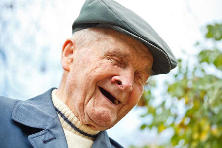 Outdoor portrait of smiling senior man in hat 