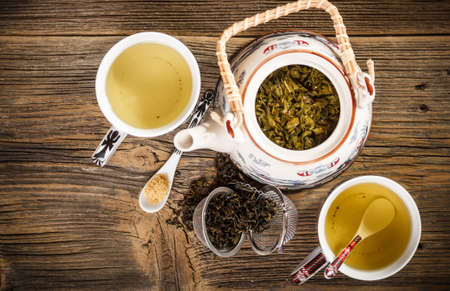 Teapot and a cup of green tea on wooden tableの写真素材