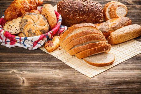 Variety of bread and buns on old wooden background