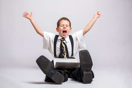 Happy little business boy with a laptop