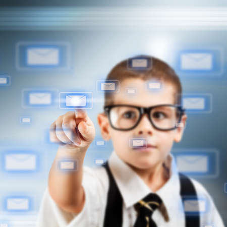 Little boy in a business suit pushing email icon on touch screen interfaceの写真素材