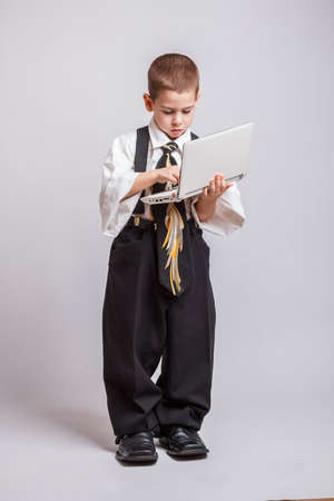 Boy typing on laptop wearing oversized clothesの写真素材