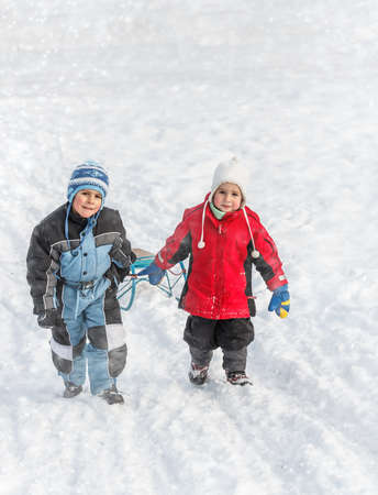 Brothers going up on a hill pulling a sledgeの写真素材