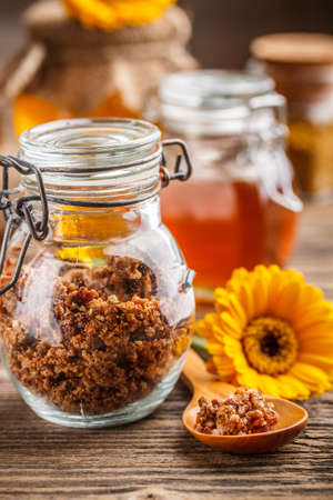 Propolis granule in glass jar, honey in backgroundの写真素材