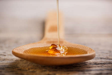 Wooden spoon with wild honey falling into itの写真素材