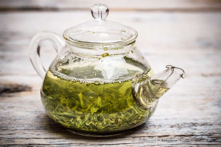 Glass teapot with green tea on wooden tableの写真素材