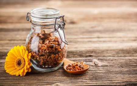 Propolis granule in glass jar on rustic wooden backgroundの写真素材