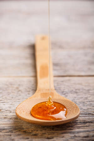 Honey pouring into wooden spoonの写真素材