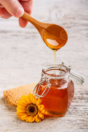 Honey with wood spoon pouringの写真素材