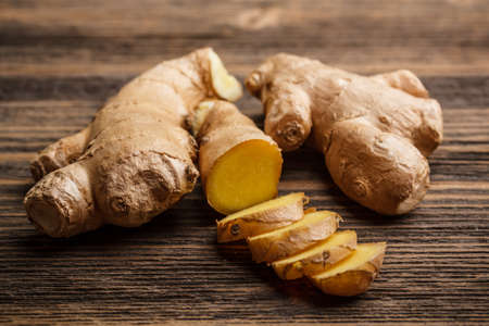 Fresh ginger, whole and sliced on rustic wooden backgroundの写真素材