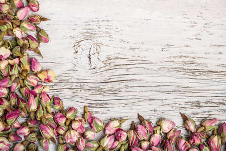 Dry tea rose bud frame on old wooden backgroundの写真素材