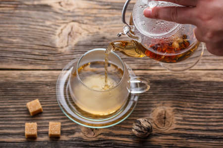 Hot flowering tea being poured into glass teacupの写真素材
