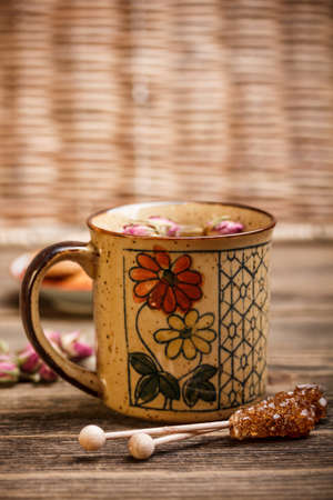 Mug of tea with flower symbol on rustic wooden tableの写真素材
