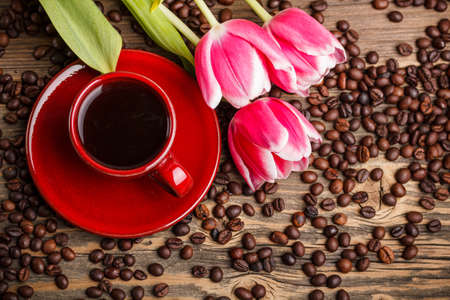 Red cup of coffee with tulips on rustic wooden table の写真素材