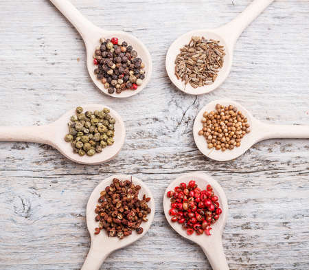 Six spoons of spices like circle on old wooden board 