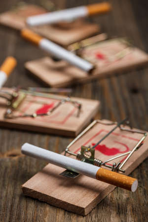 Cigarette in mousetrap on old wooden backgroundの写真素材